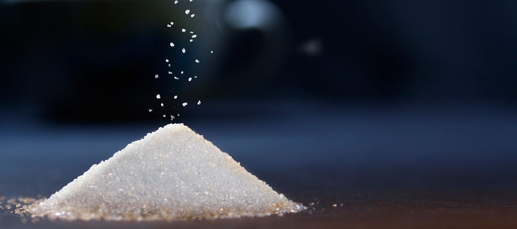 Refined sugar being sprinkled in top of a pile