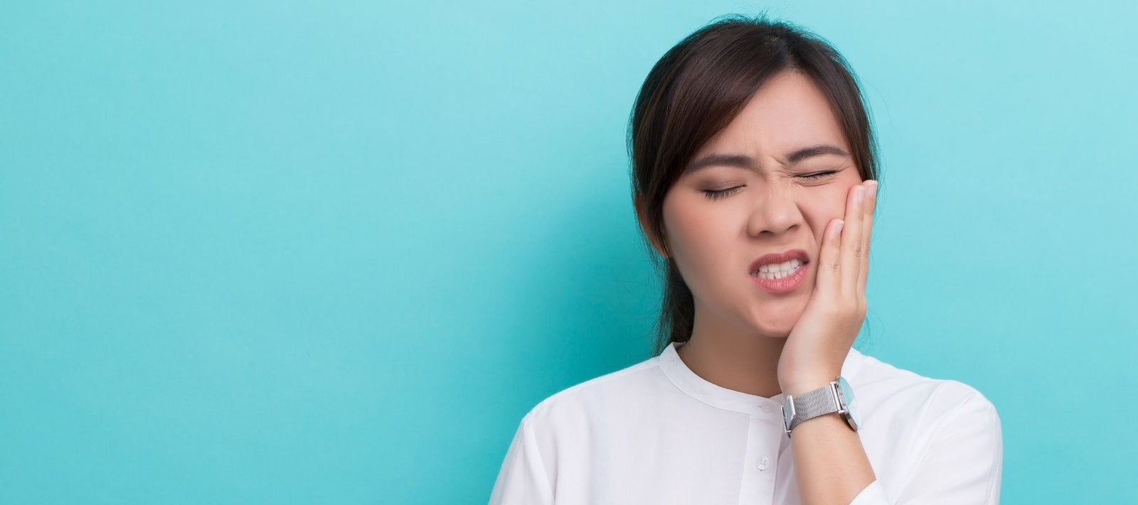 Woman Hurting Her Teeth By Chewing on Breath Mints Against a Blue Background