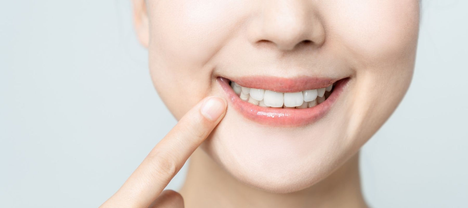 Woman smiling and pointing to her fresh and clean teeth
